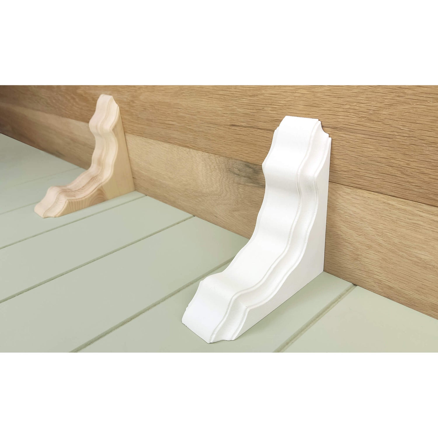 White corbel bracket on a wooden wall with a light green baseboard.