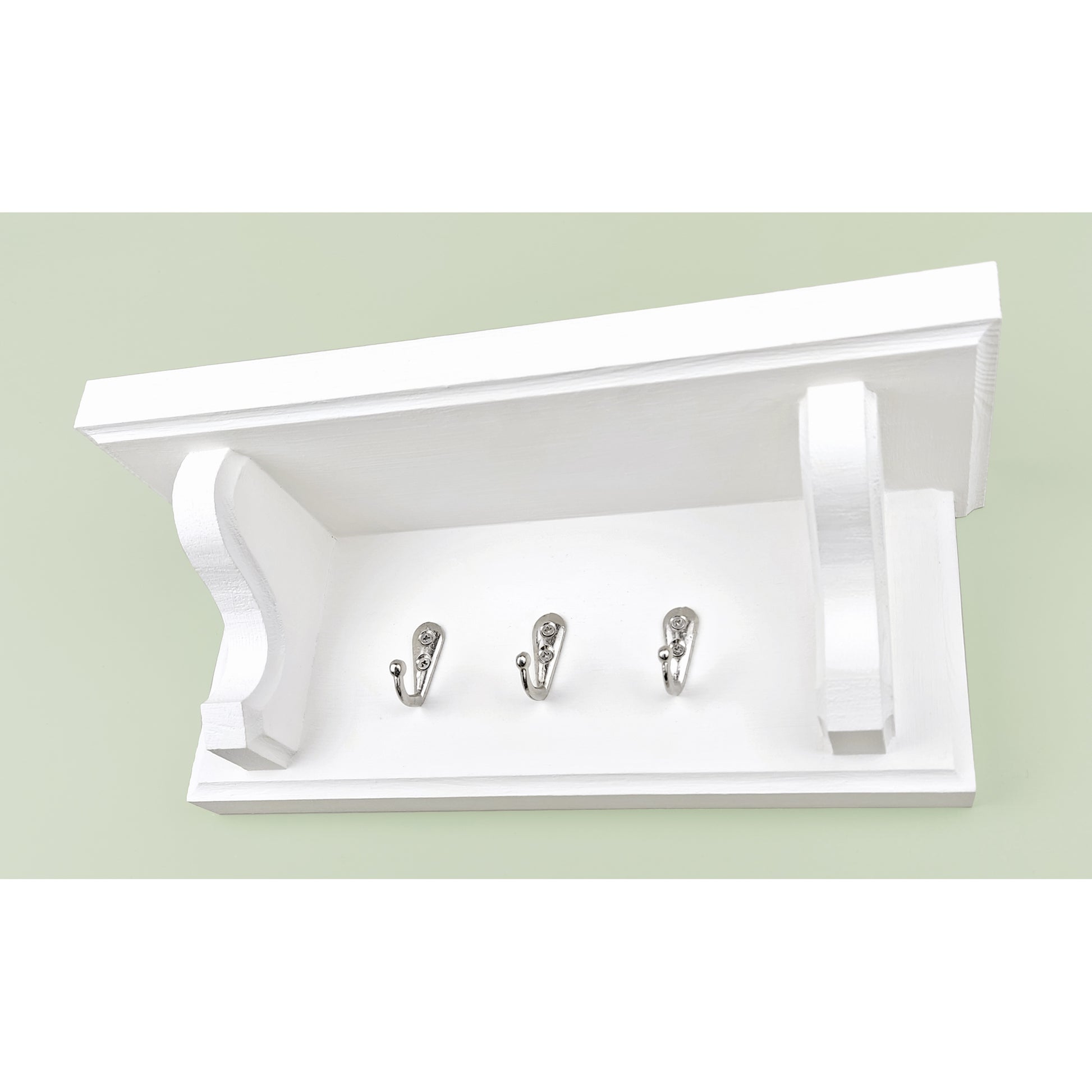 A solid wooden white chalk painted key rack with shelf and chrome key hooks on a green background