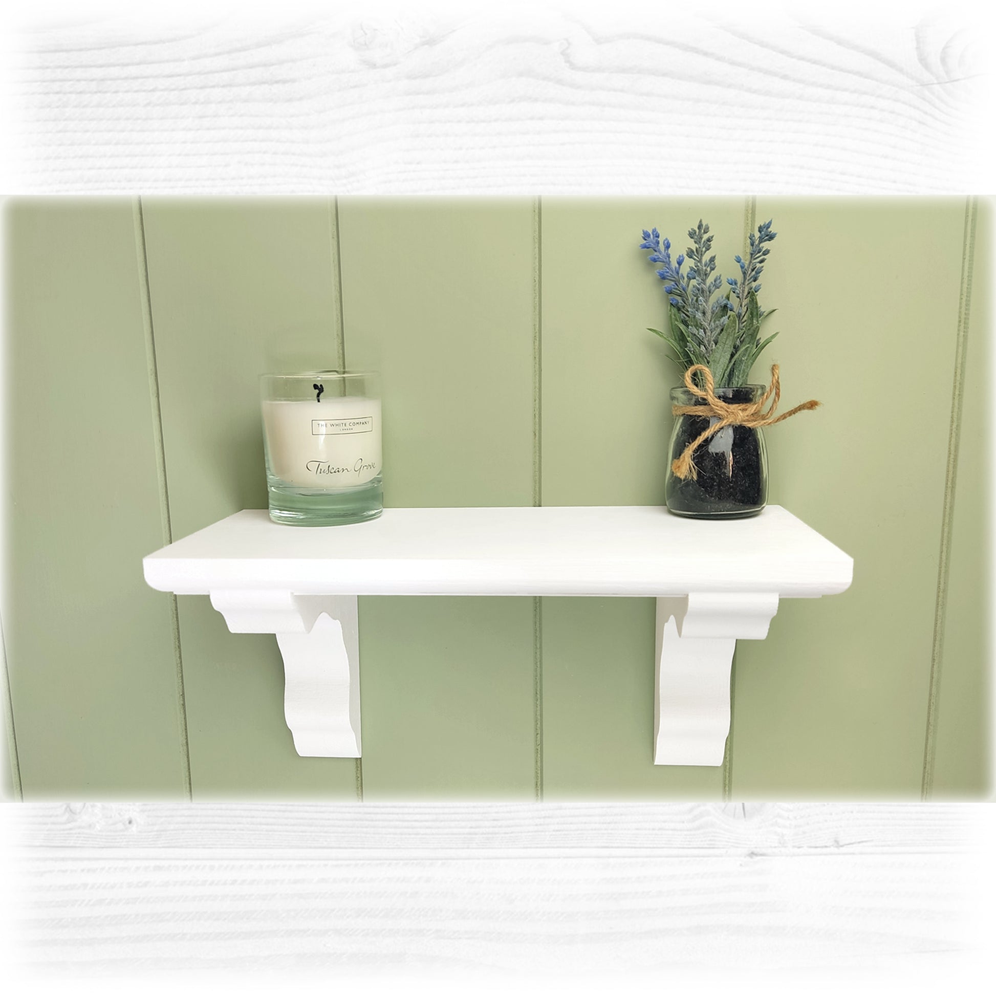 A chalk painted white wooden floating shelf with a green cladded background
