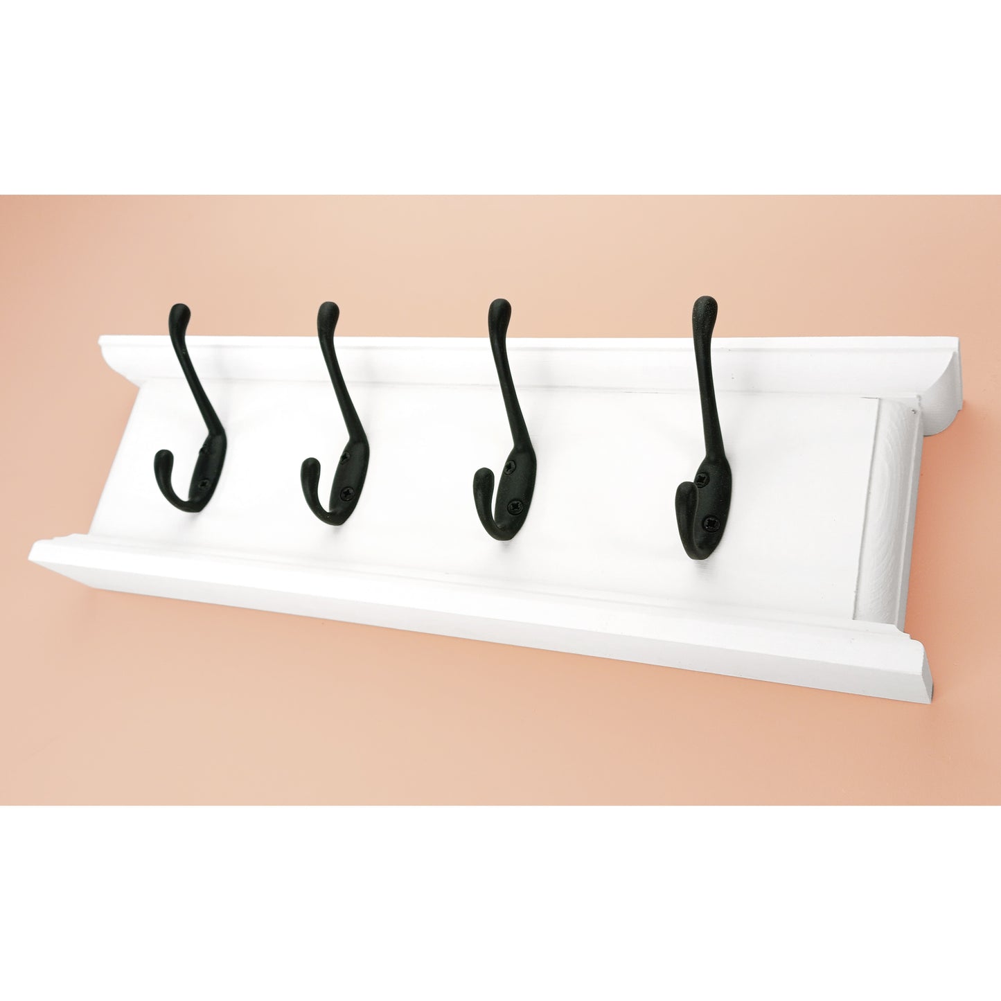 White wall-mounted rack with four black hooks on a beige background