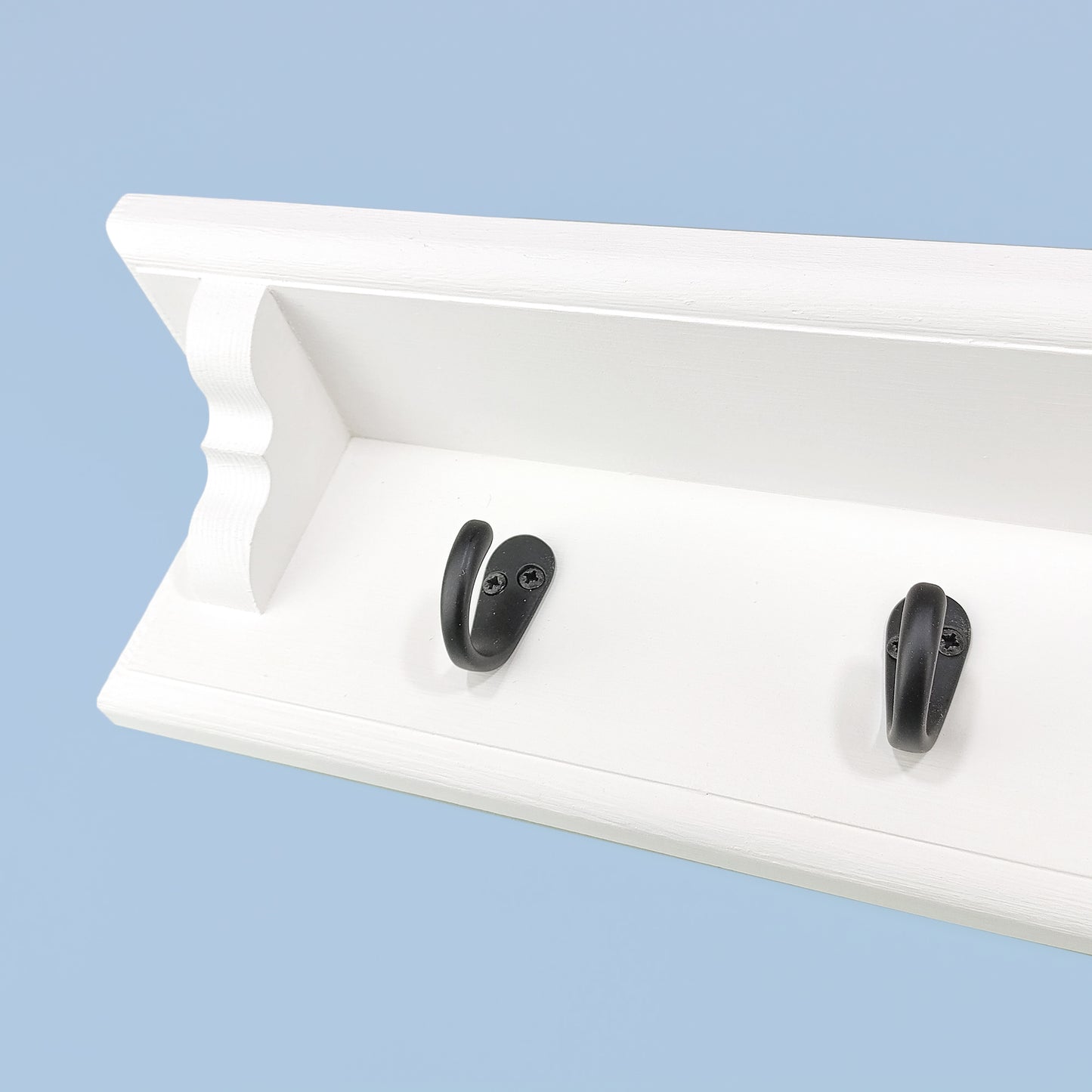 A coat rack with shelf and single metal hooks on a blue background