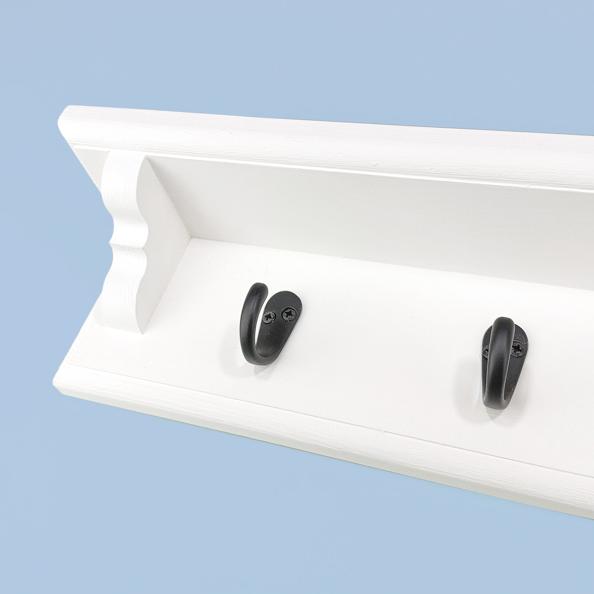 A coat rack with shelf and single metal hooks on a blue background