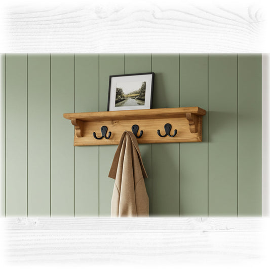 Wooden shelf with hooks against a green paneled wall with a framed picture.