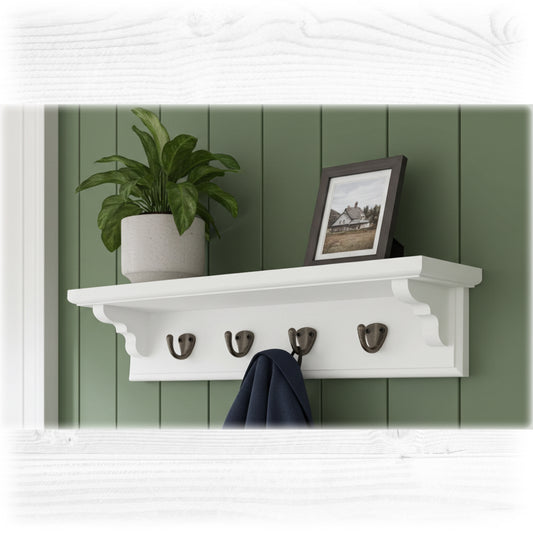 White wall shelf with hooks against a green paneled wall