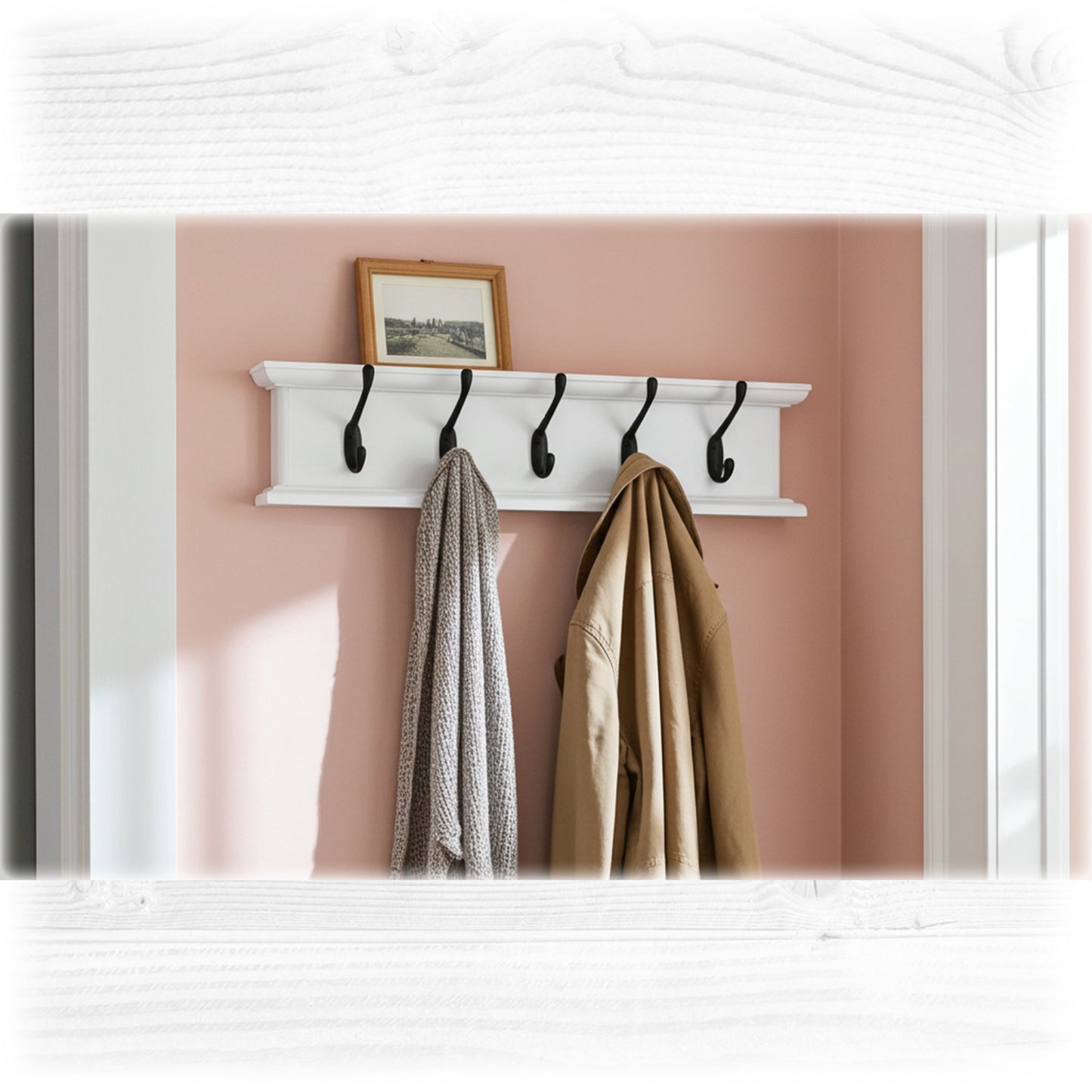 White wall-mounted coat rack with hooks holding coats against a pink wall.