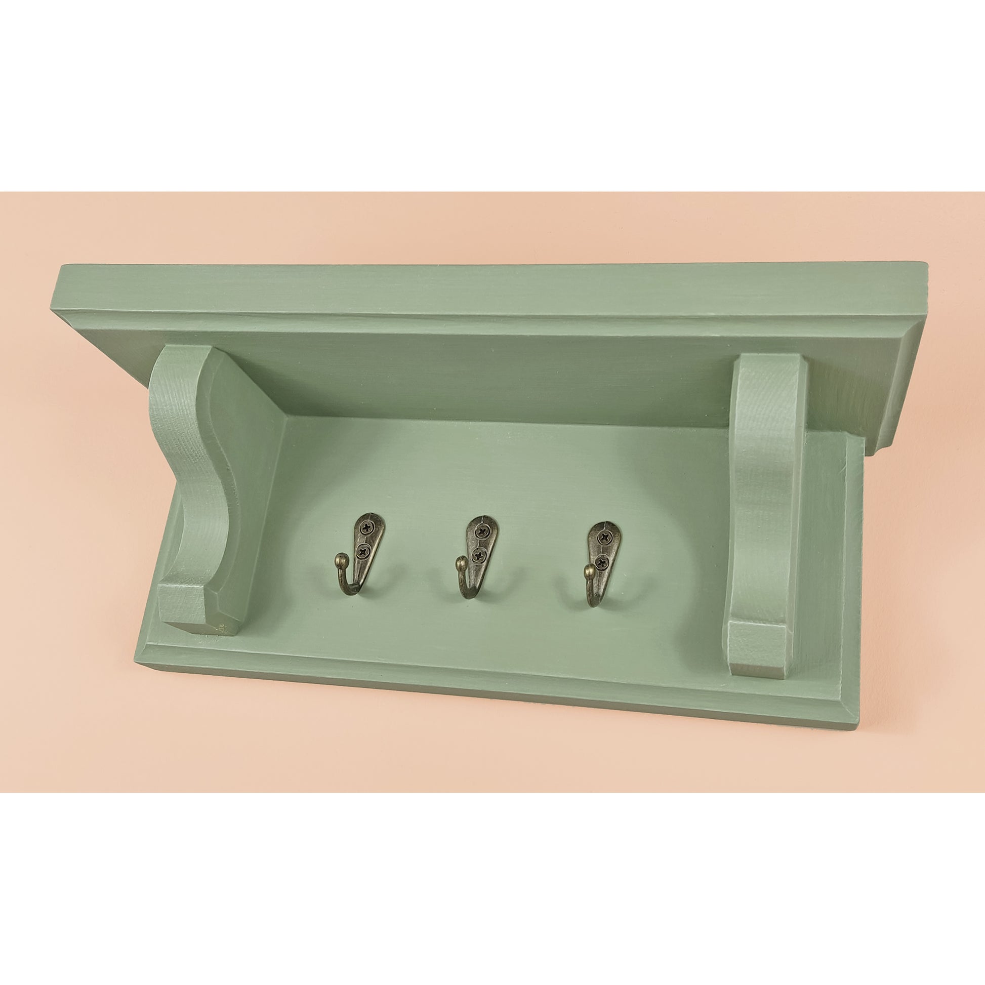 Green wall shelf with three hooks on a beige background
