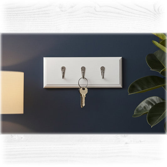 Key holder with three hooks on a dark blue wall, with a key hanging from one of the hooks.