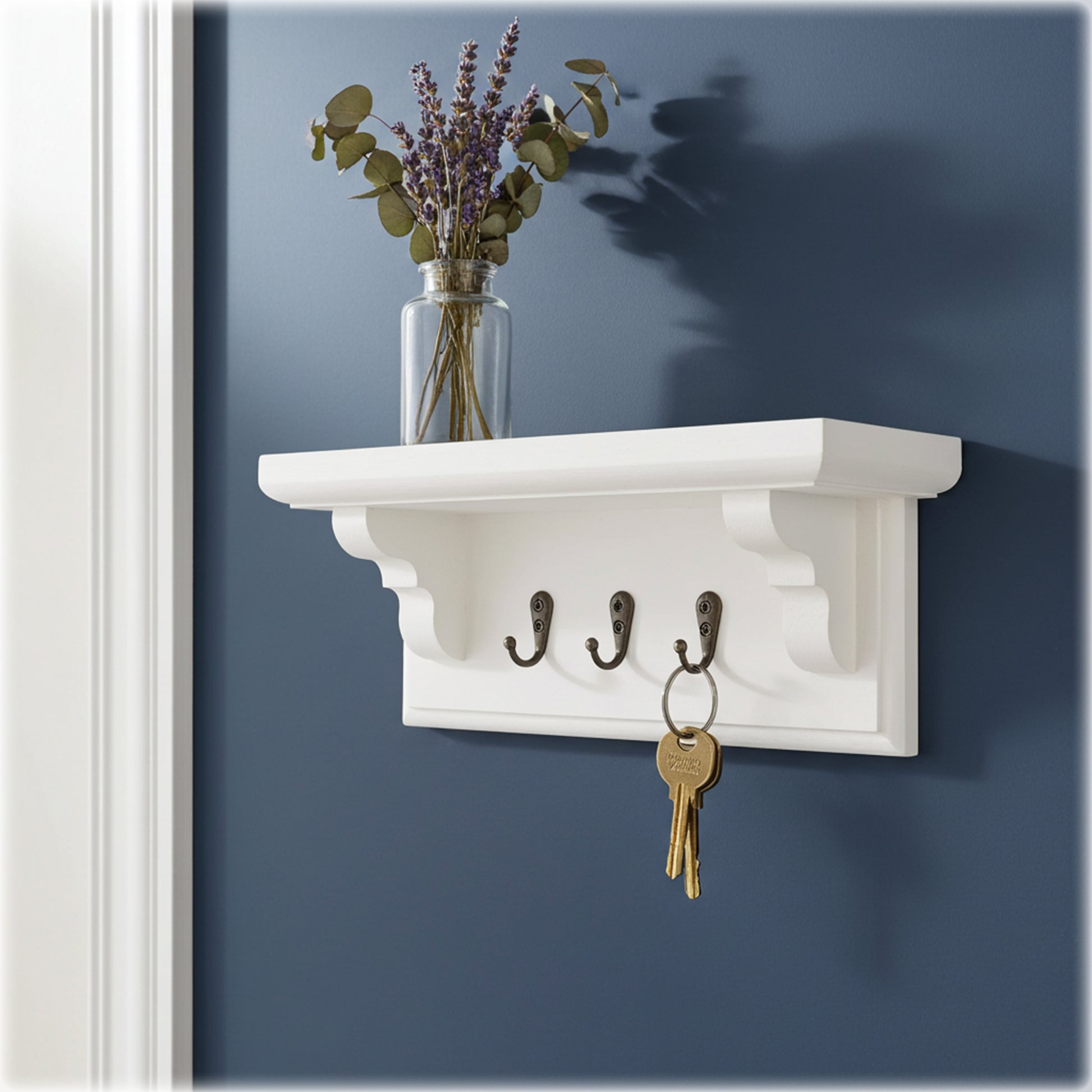 White wall shelf with hooks and a vase of flowers on a blue wall