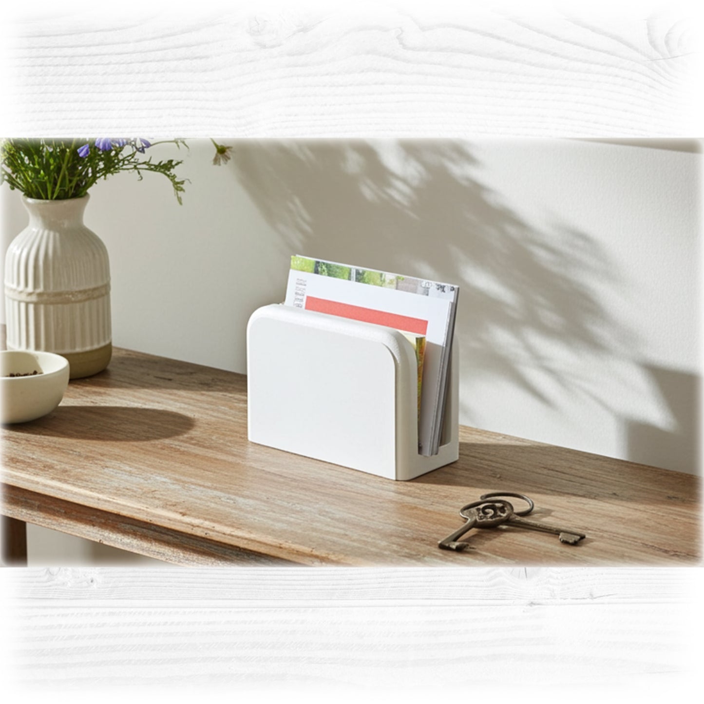 White magazine holder on a wooden surface with a vase and key in the background