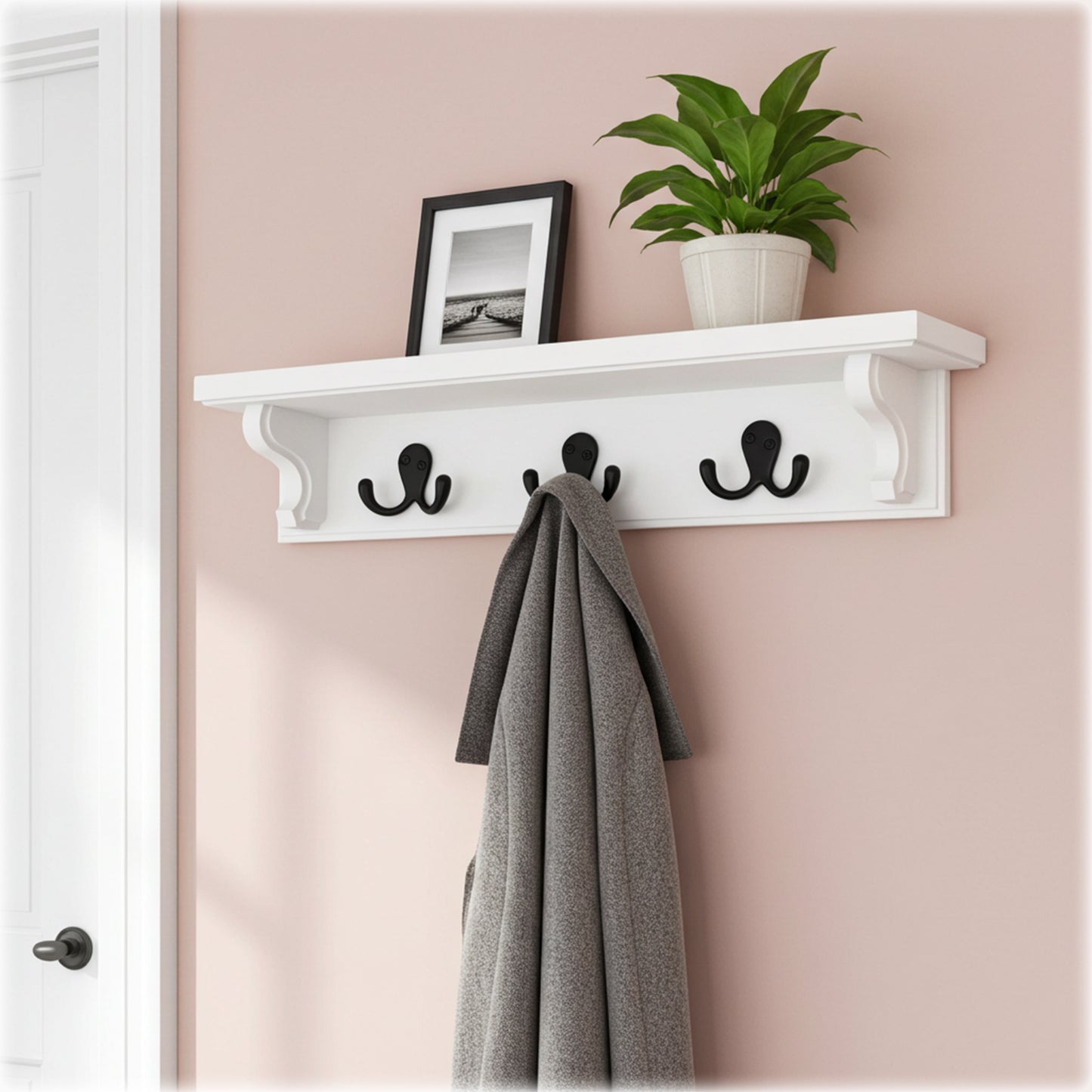 White wall shelf with hooks holding a coat and a plant against a pink wall.