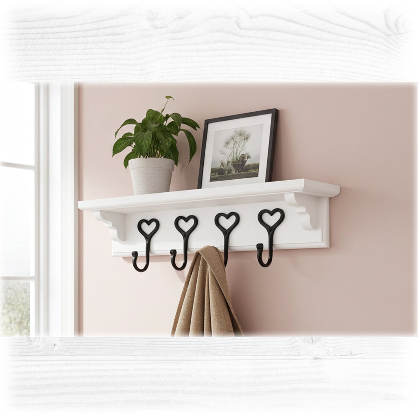 White wall shelf with heart-shaped hooks, plant, and picture frame against a pink wall.