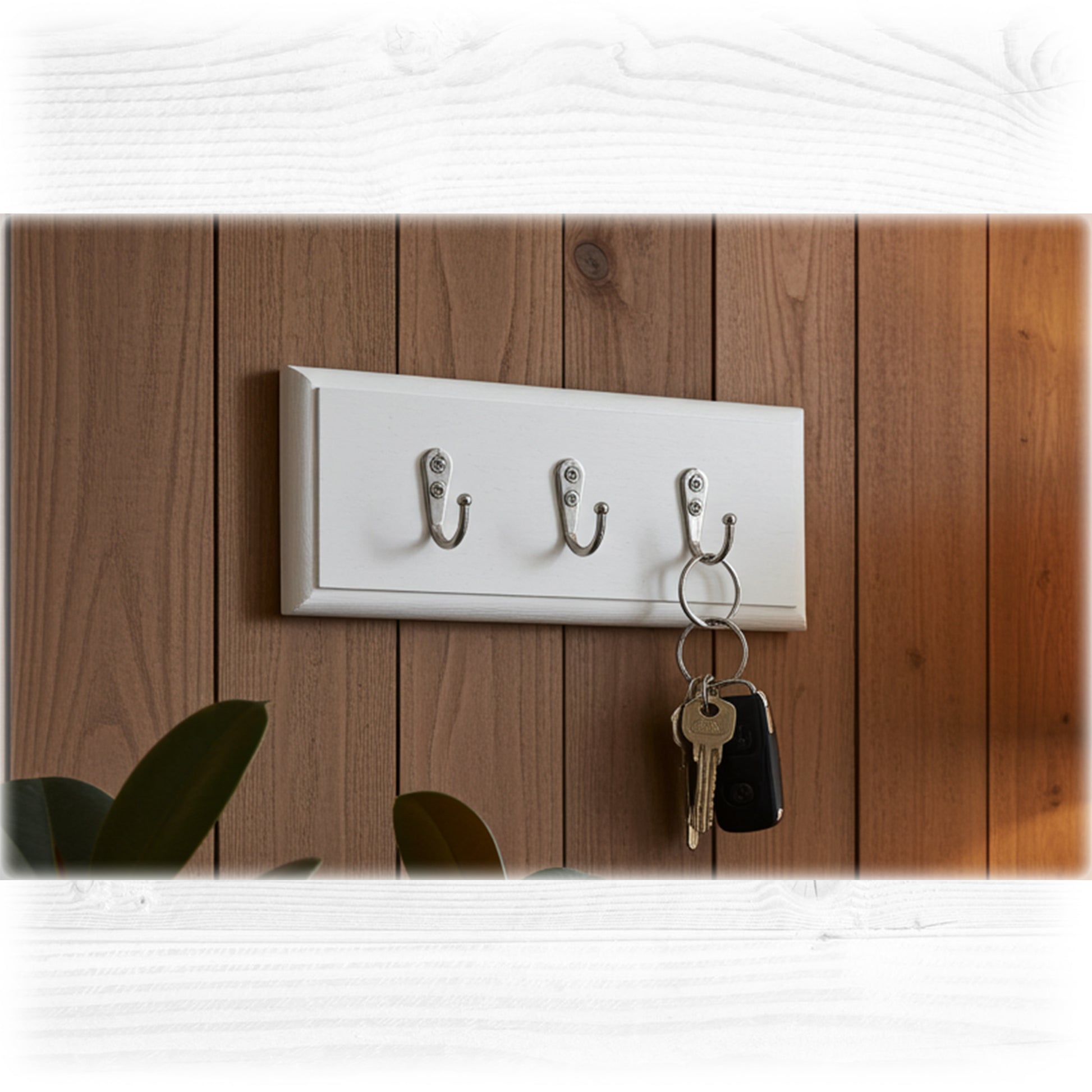 White wall-mounted hook with three hooks on a wooden panel background