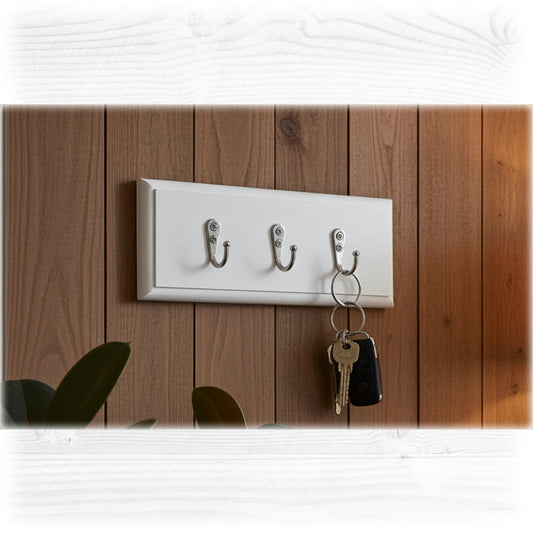 White wall-mounted hook with three hooks on a wooden panel background