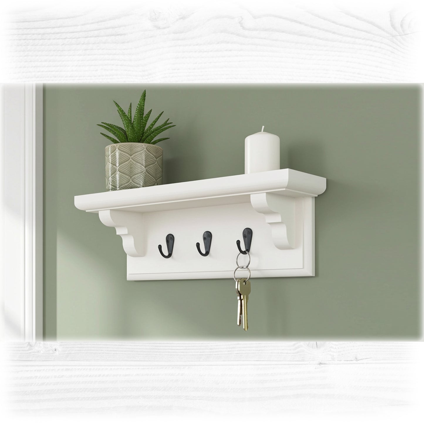White wall shelf with hooks, plant, and candle against a green wall.