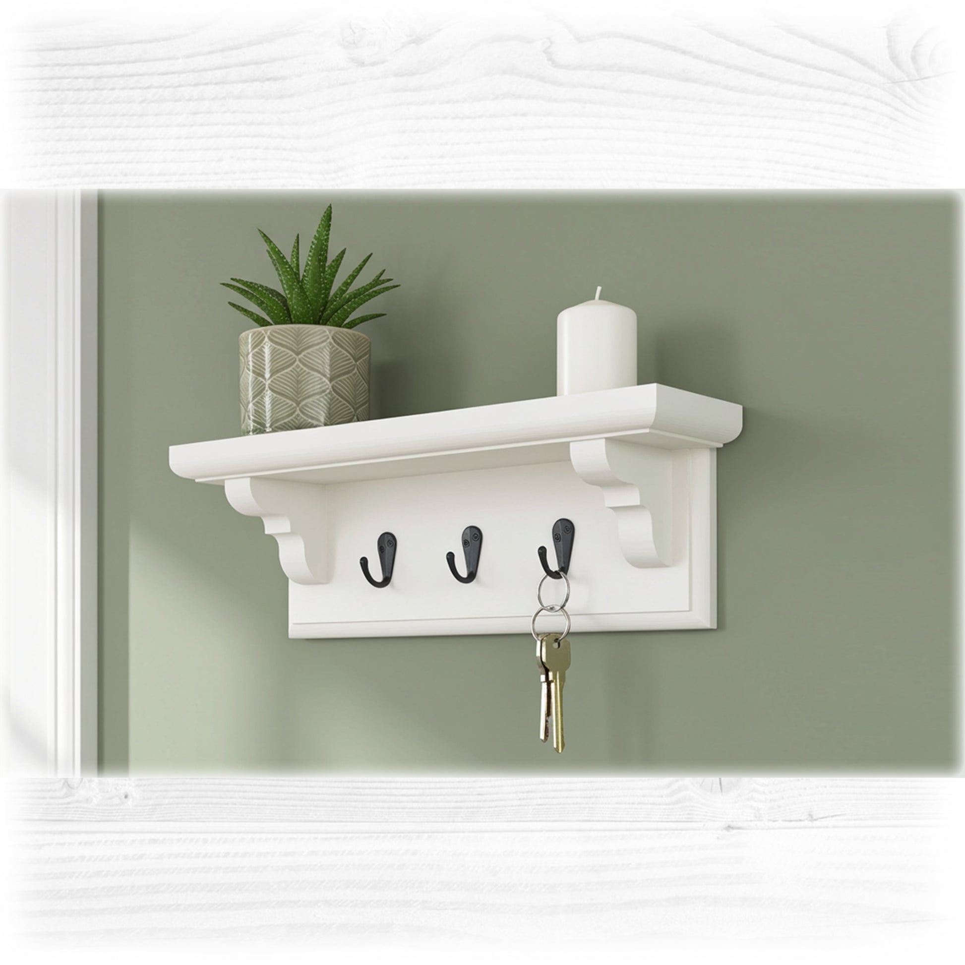 White wall shelf with hooks, plant, and candle against a green wall.